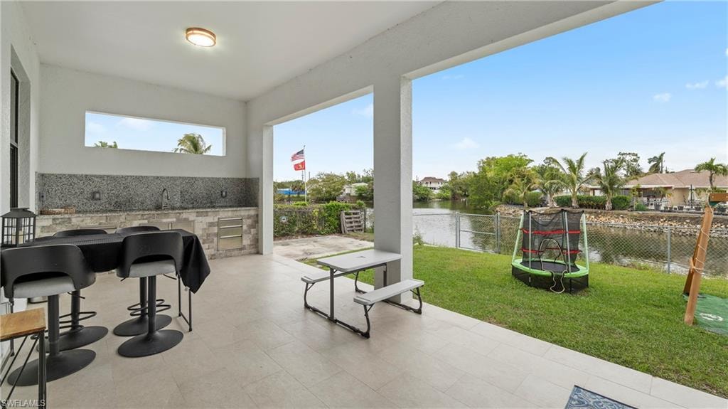 Fenced backyard with a patio area, a water view, and a trampoline