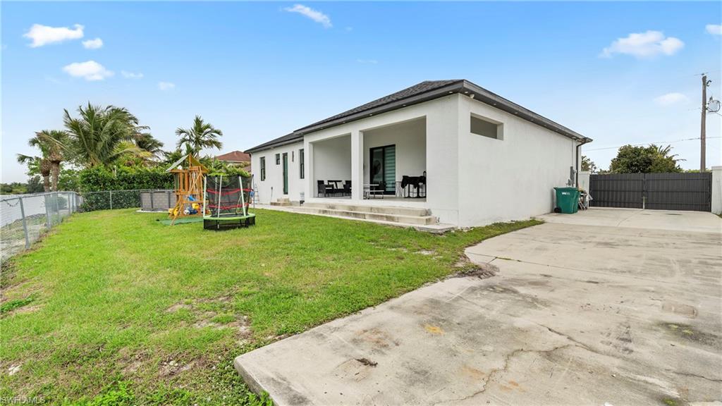 Back of property with a fenced backyard, a playground, stucco siding, a patio, and a trampoline
