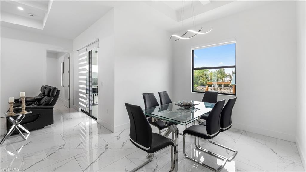 Dining space featuring light marble finish flooring and a tray ceiling
