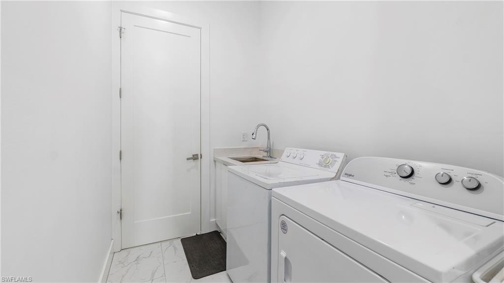 Laundry area with light marble finish flooring and separate washer and dryer