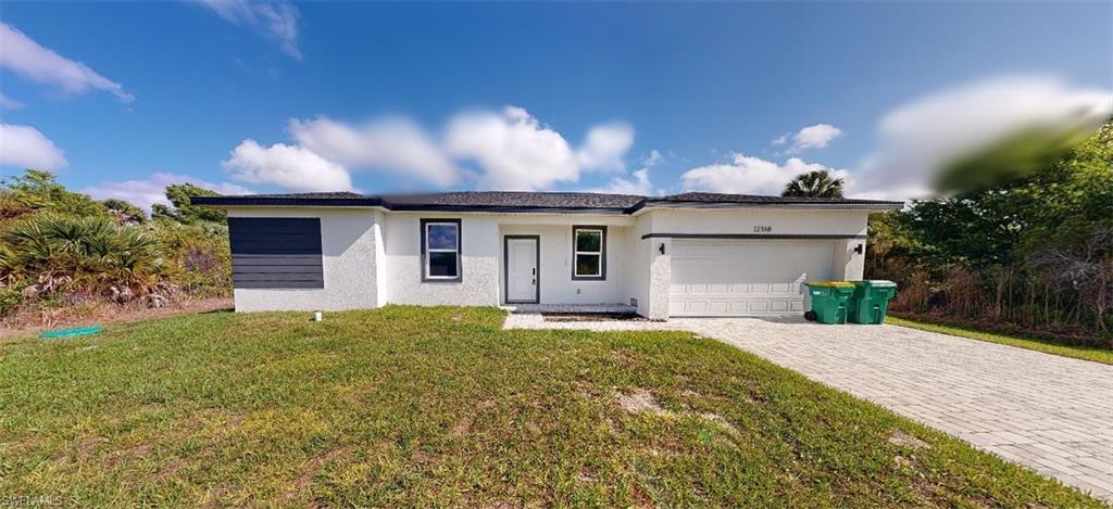 Ranch-style house with a front lawn, stucco siding, an attached garage, and decorative driveway