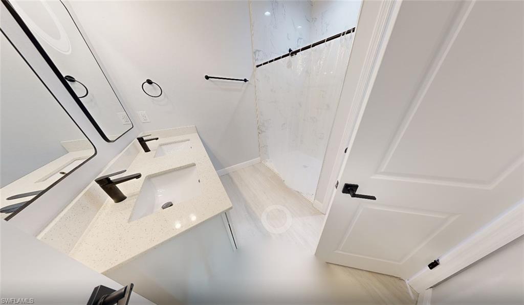 Bathroom with double vanity and a marble finish shower