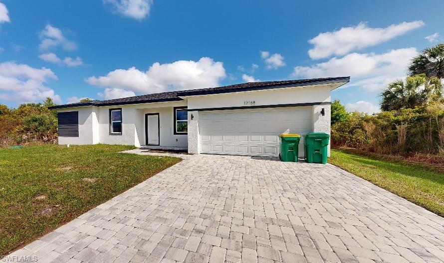 Single story home with a front yard, stucco siding, decorative driveway, and an attached garage