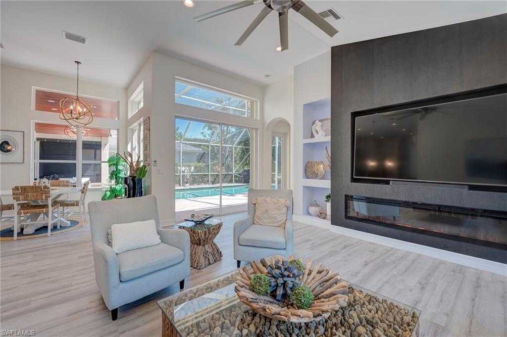 Living area with built in shelves, a ceiling fan, hanging lights, light wood-type flooring, and a sunroom