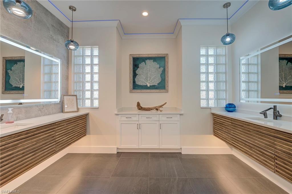 Full bath with two vanities, crown molding, dark tile patterned floors, and recessed lighting