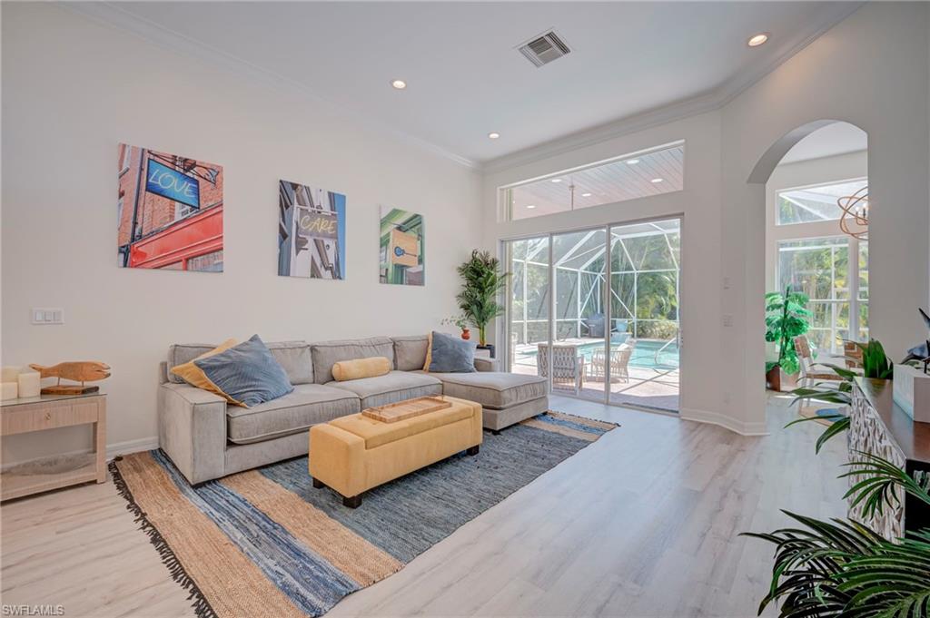 Living room featuring a sunroom, light wood-style floors, crown molding, and recessed lighting