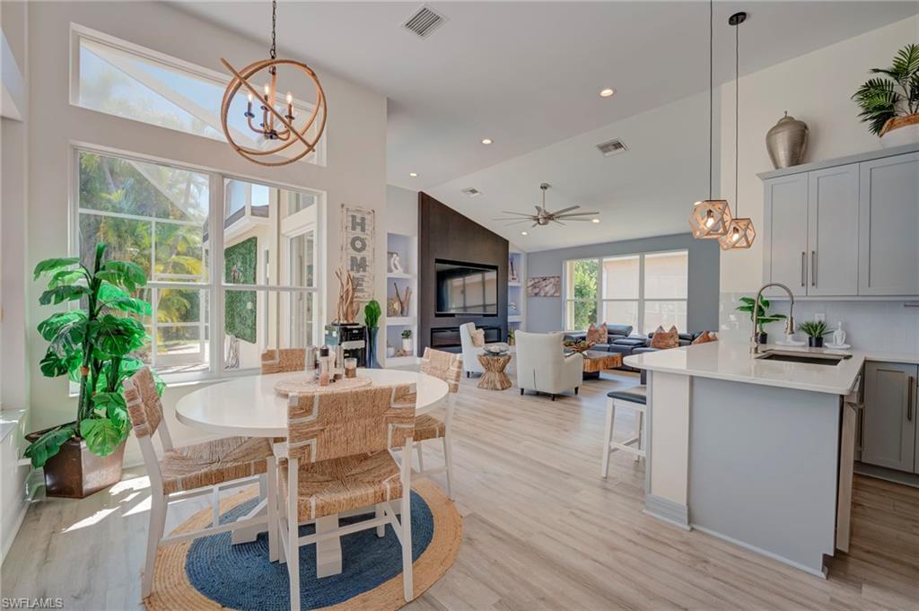 Dining area featuring a chandelier, light wood-type flooring, ceiling fan, and vaulted ceiling