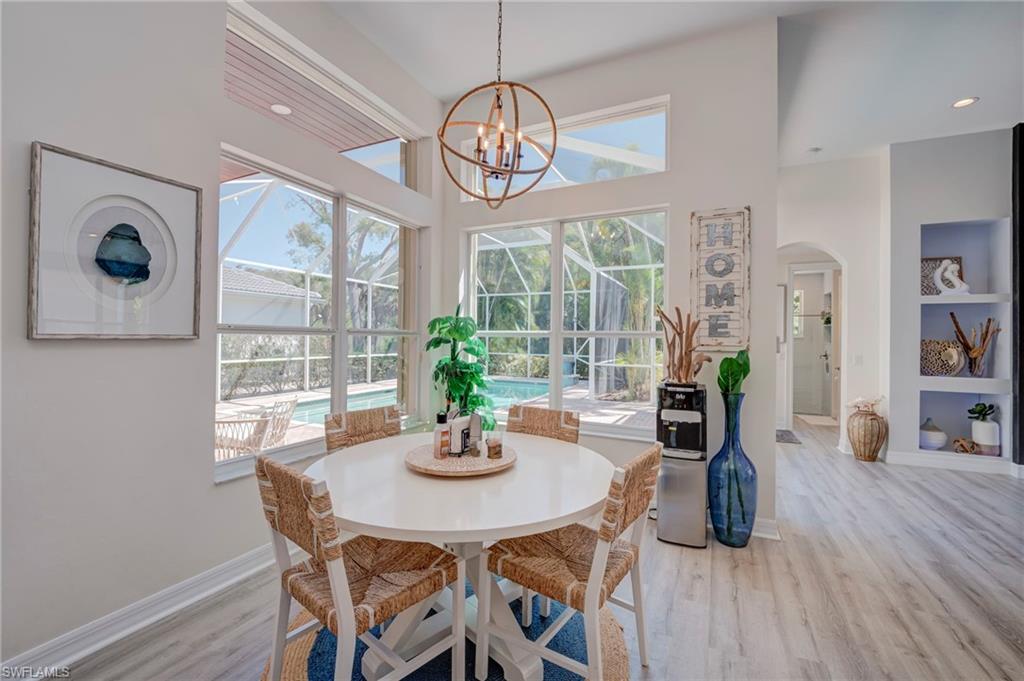 Dining area with arched walkways, light wood-style flooring, hanging lights, and built in shelves