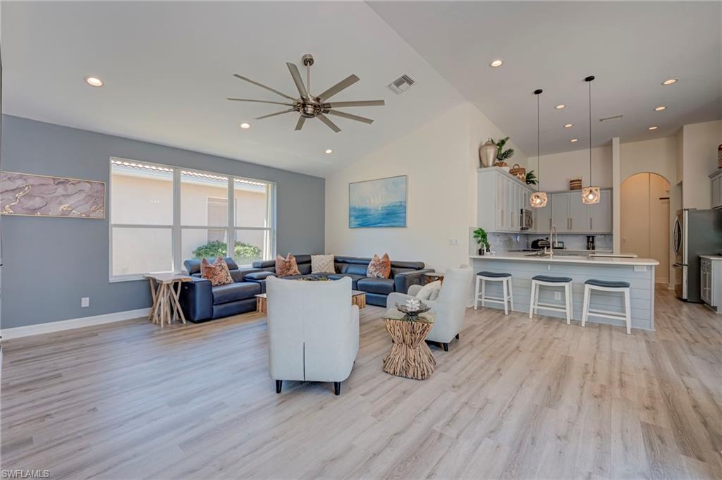 Living room with ceiling fan, recessed lighting, light wood finished floors, arched walkways, and lofted ceiling