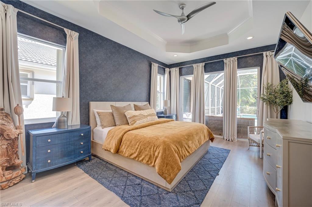 Bedroom featuring access to outside, light wood-style floors, ceiling fan, multiple windows, and ornamental molding
