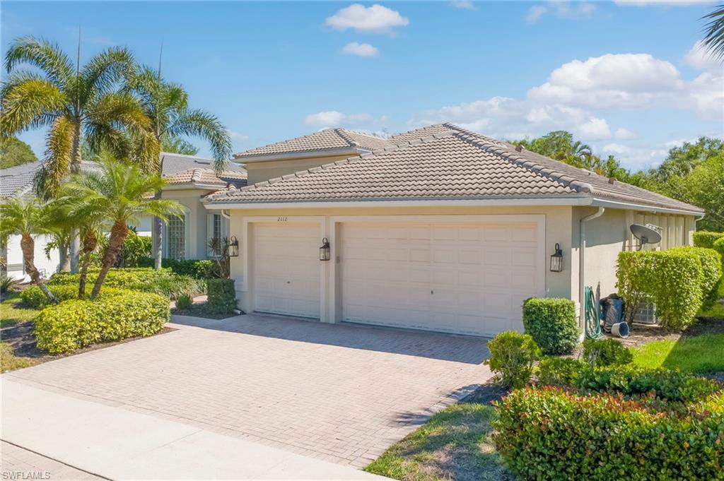 Mediterranean / spanish-style house with an attached garage, decorative driveway, stucco siding, and a tiled roof