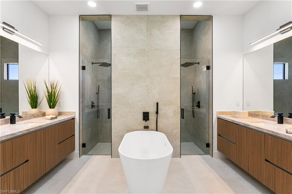 SPA-STYLE BATH featuring dual shower system, freestanding tub & marble vanities