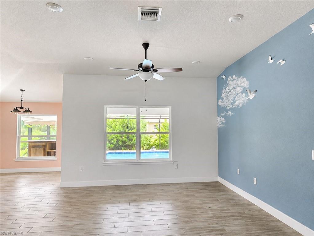 VIRTUALLY STAGED Kitchen with open floor plan, a kitchen breakfast bar, stainless steel appliances, light stone countertops, and light wood finished floors