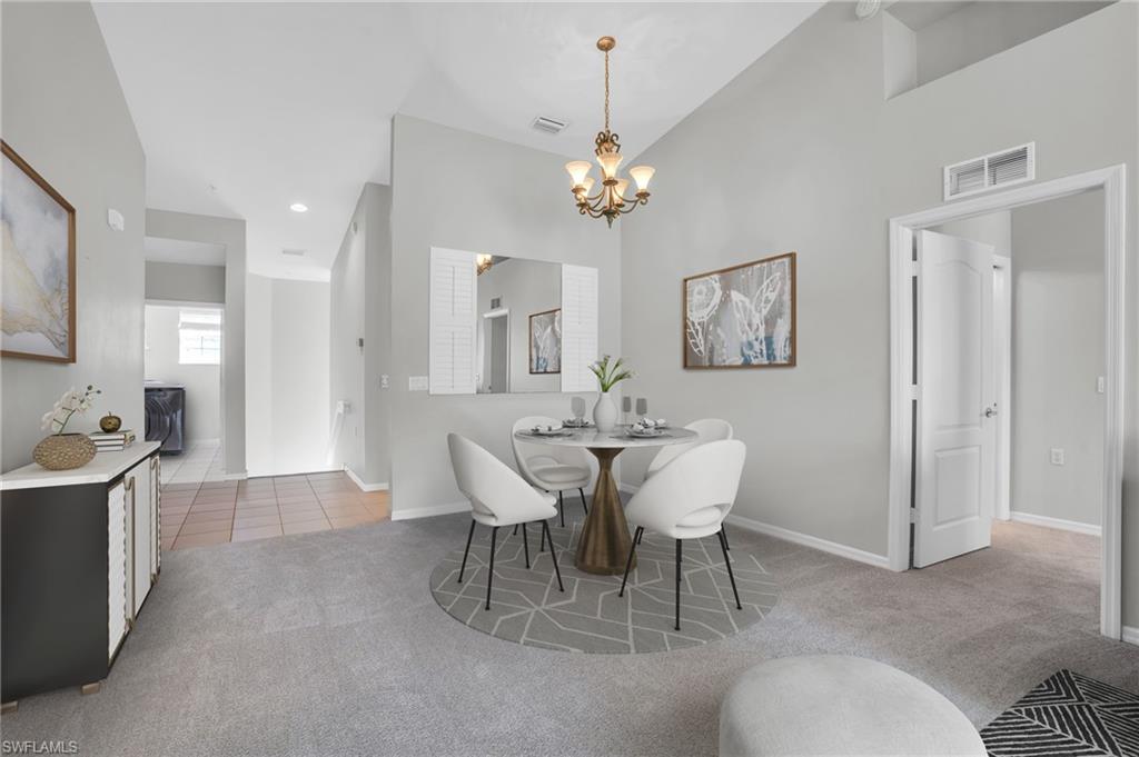 Carpeted dining area with an inviting chandelier and lofted ceiling