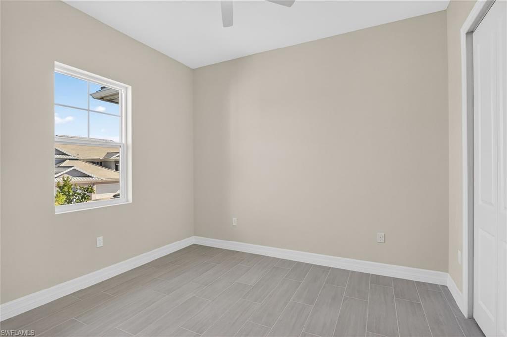 Empty room with a ceiling fan and wood tiled floors