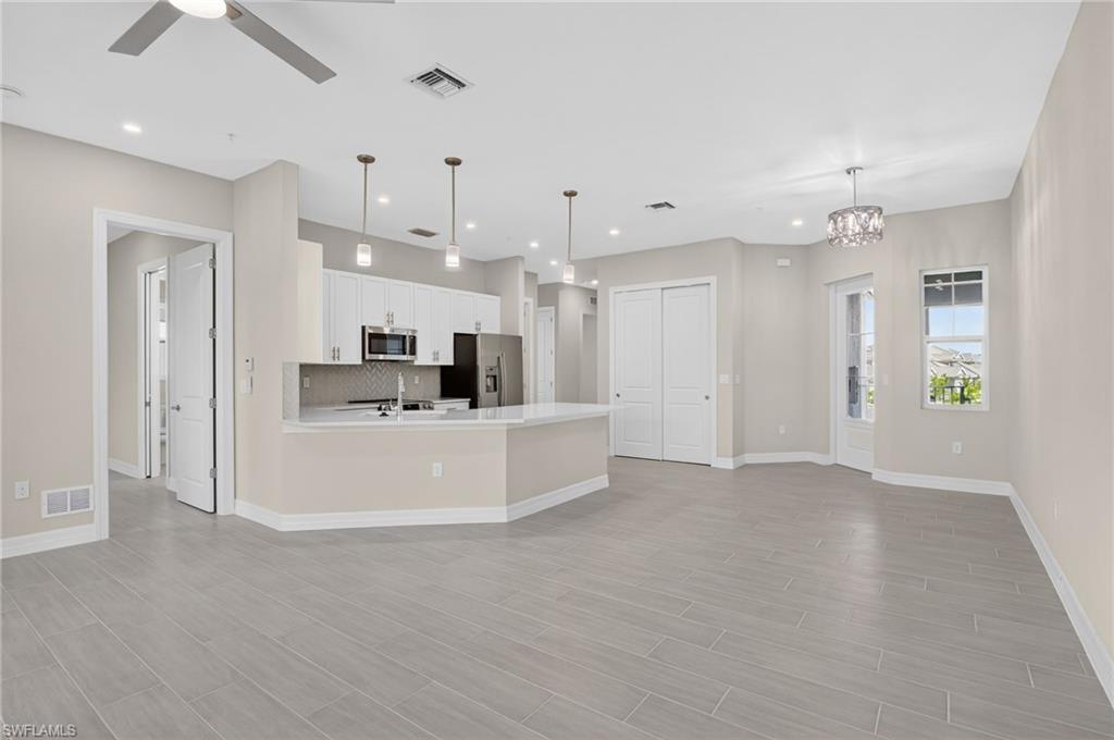 Kitchen with white cabinets, stainless steel appliances, open floor plan, ceiling fan, and a peninsula