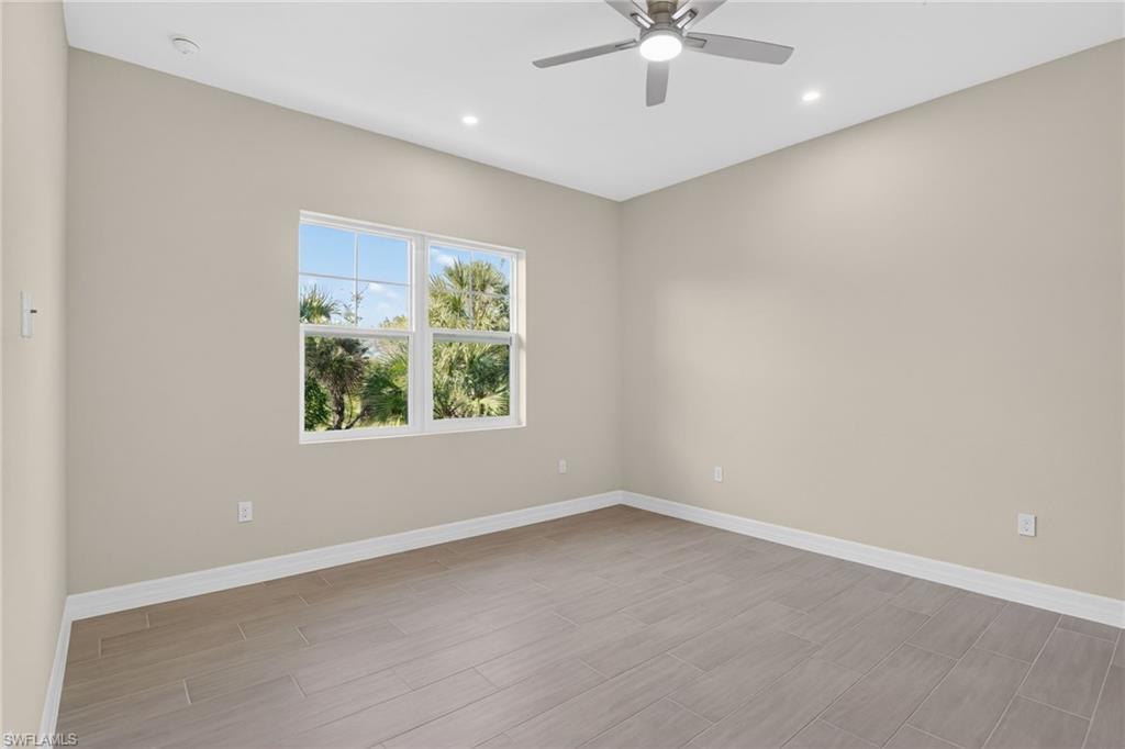 Empty room featuring ceiling fan, wood tiled floors, and recessed lighting