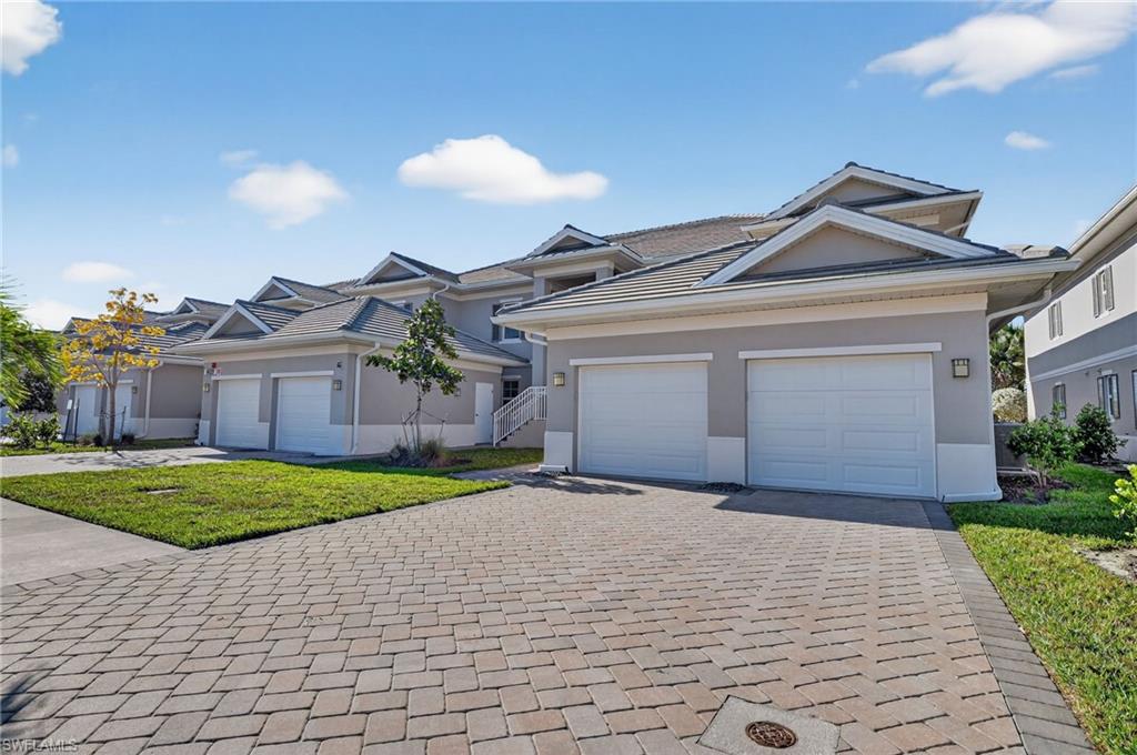 Ranch-style house featuring a front lawn, decorative driveway, stucco siding, and an attached garage