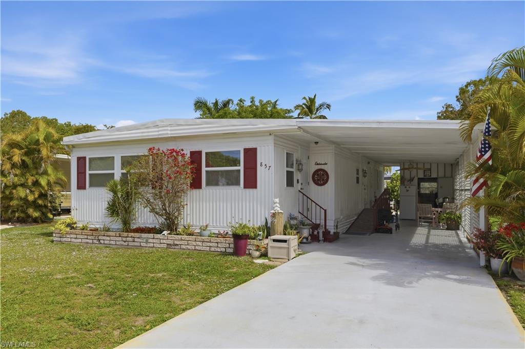 Exterior featuring white vertical siding, red window shutters, and a covered carport