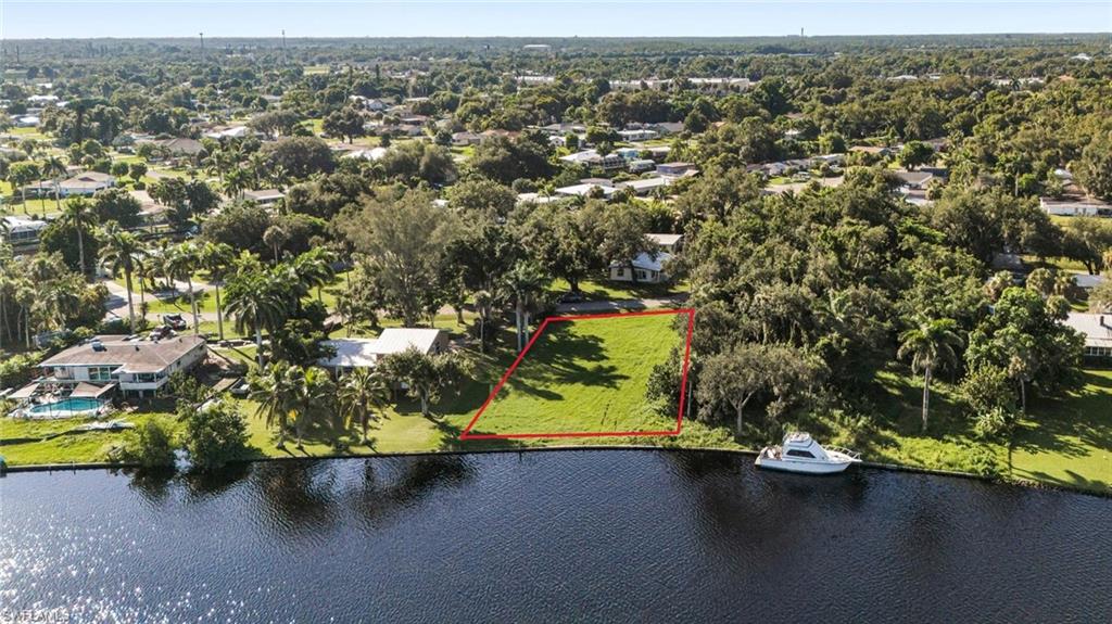 Aerial view of property and surrounding area featuring property parcel outlined and a nearby body of water