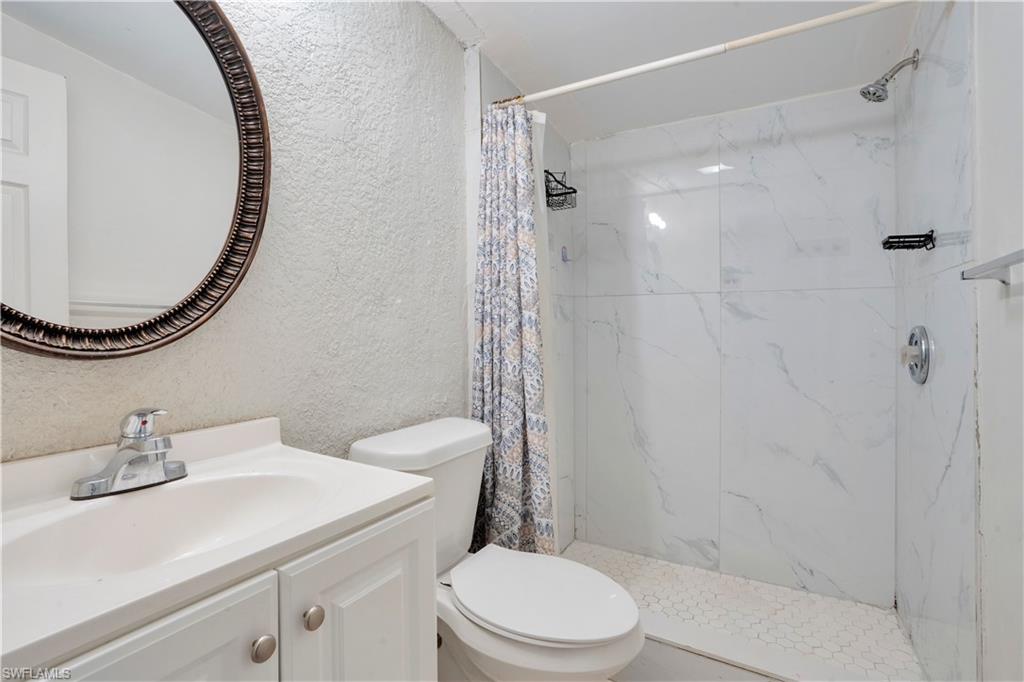 Full bathroom featuring a textured wall, vanity, and a marble finish shower