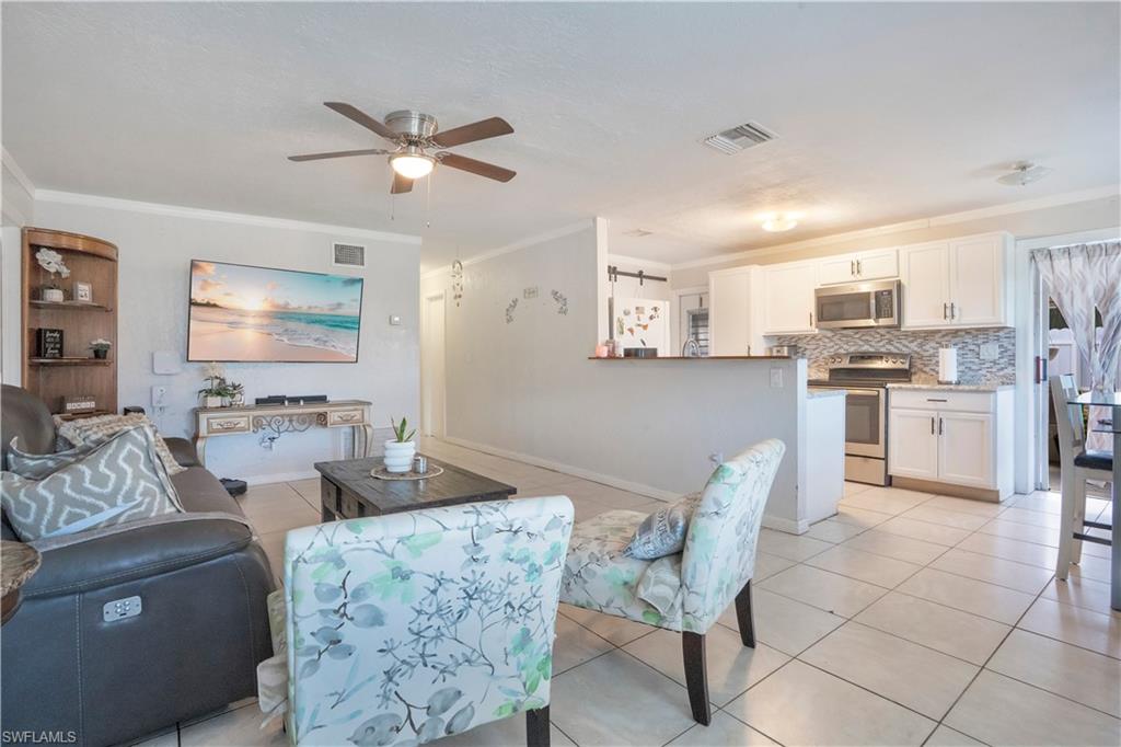 Living room featuring ornamental molding, ceiling fan, and light tile patterned floors