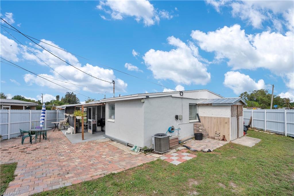 Back of property featuring a patio, a fenced backyard, stucco siding, and a storage shed