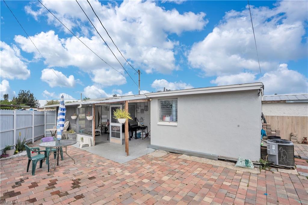 Back of property with a fenced backyard, a patio, stucco siding, a sunroom, and outdoor dining area
