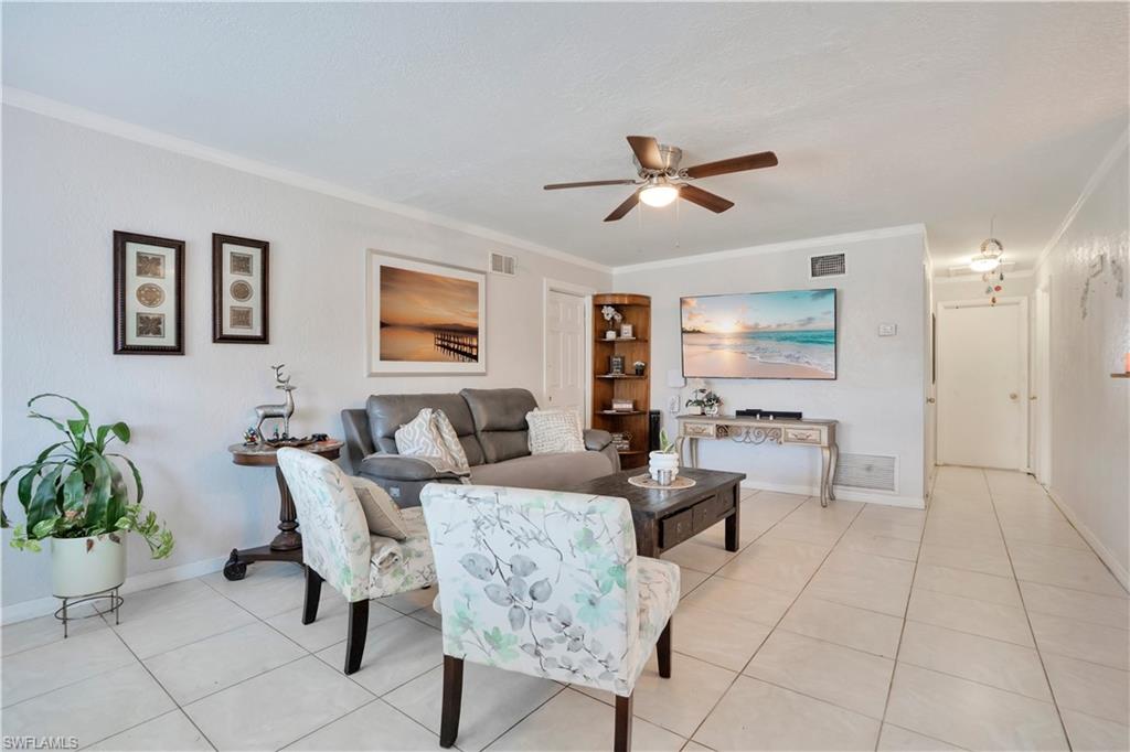 Living area featuring crown molding, ceiling fan, and light tile patterned flooring
