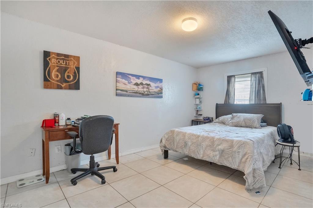 Bedroom with a desk, a textured ceiling, and light tile patterned flooring