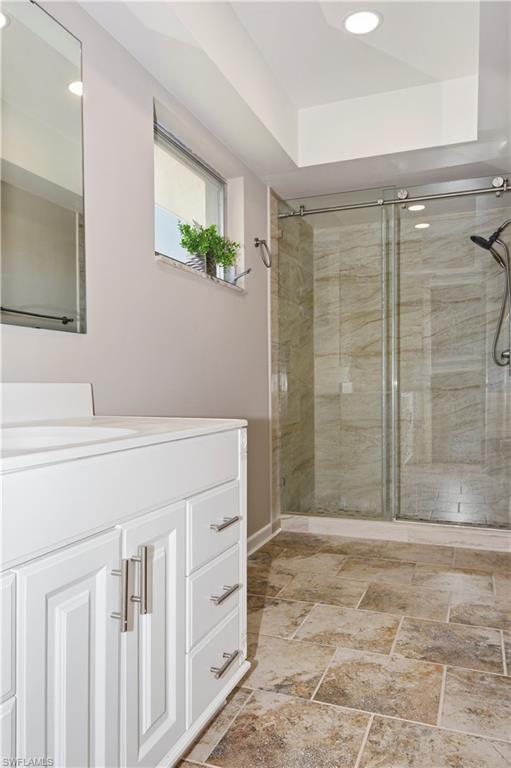 Full bath with vanity, a shower stall, recessed lighting, and stone tile floors