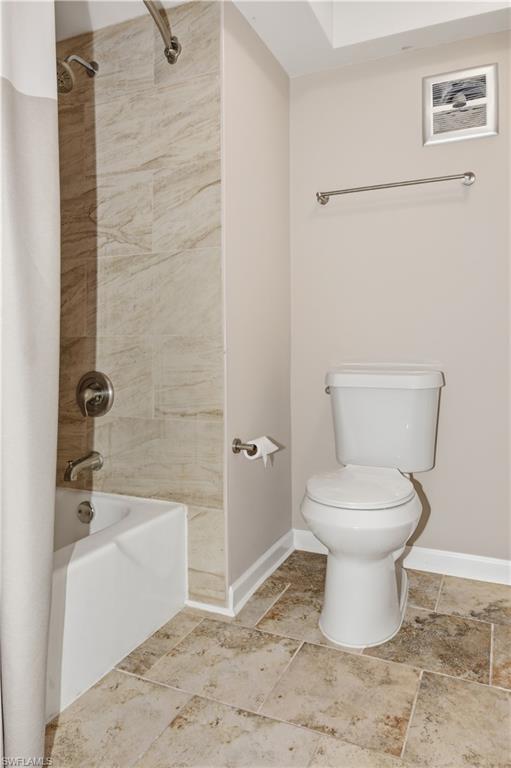 Full bathroom featuring shower / tub combo and light stone finish flooring