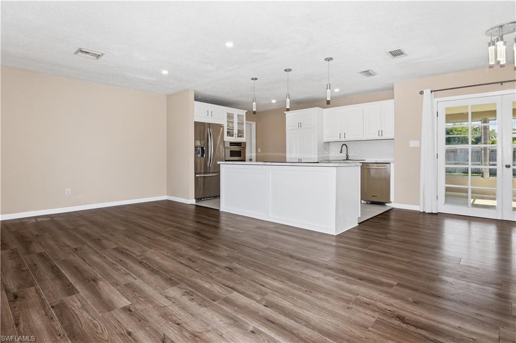 Kitchen featuring open floor plan, a kitchen island, stainless steel appliances, and white cabinets