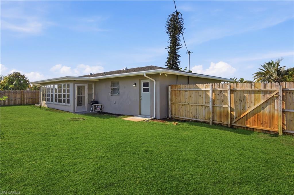 Rear view of property with a fenced backyard, stucco siding, and a gate