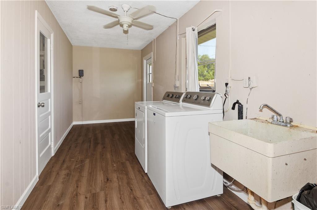 Laundry room featuring dark wood-type flooring, a ceiling fan, and washer and dryer