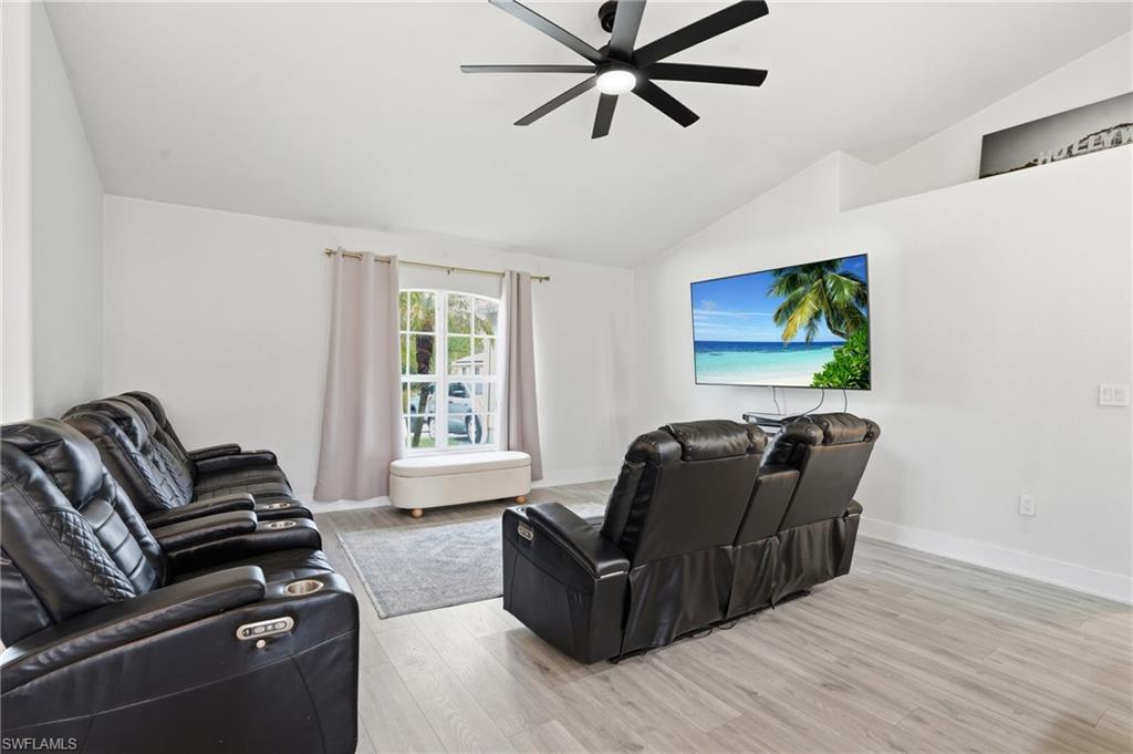 Living area with light wood-style floors, lofted ceiling, and a ceiling fan