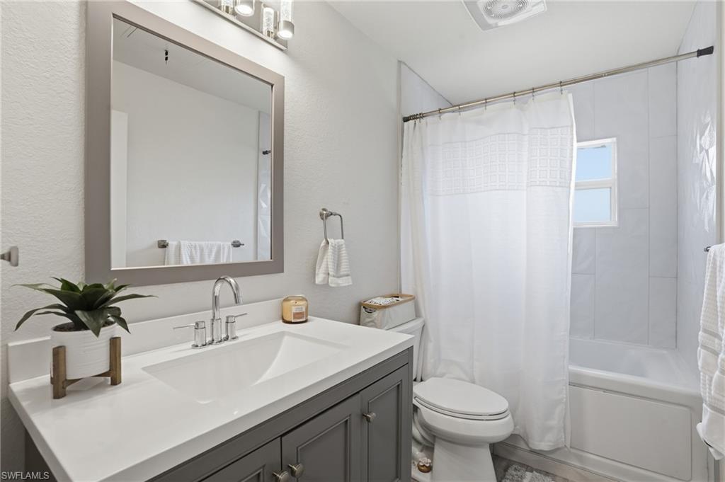 Bathroom featuring vanity and shower / bathtub combination with curtain