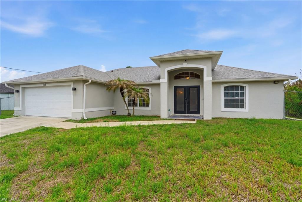 View of front of home with a garage, driveway, and stucco siding