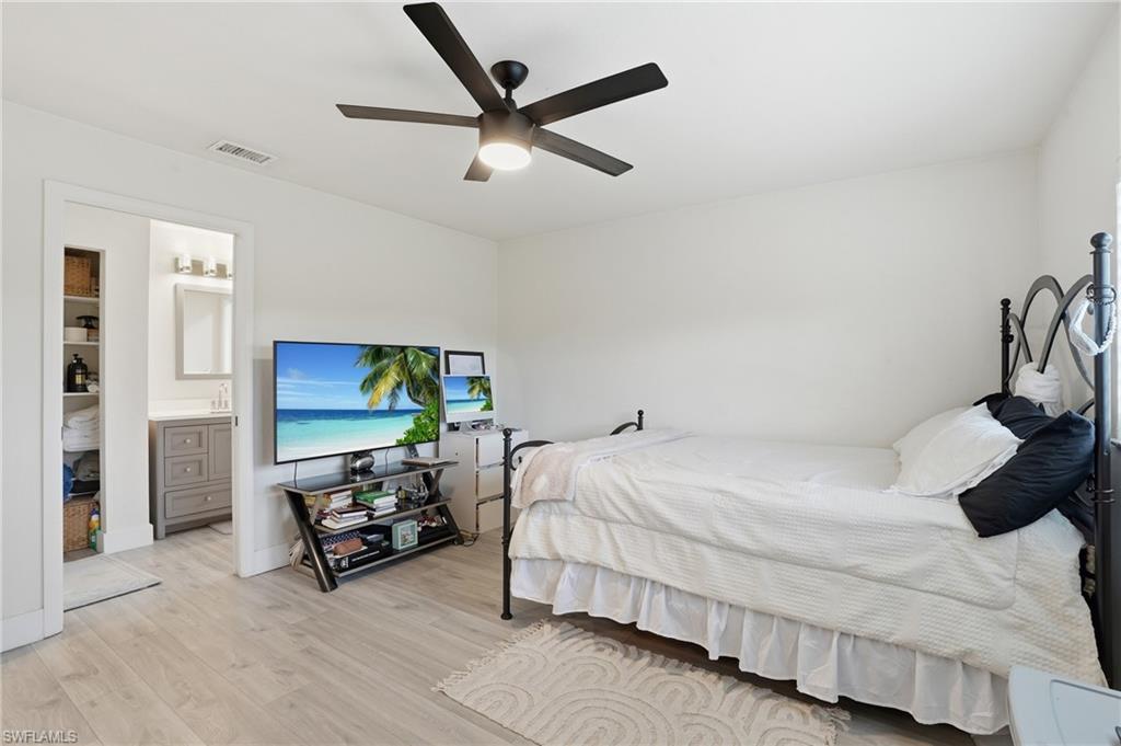 Bedroom with light wood-style flooring, ceiling fan, and ensuite bathroom