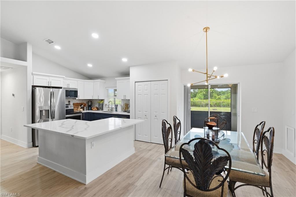 Dining room featuring suspended lighting, light wood-style floors, and lofted ceiling