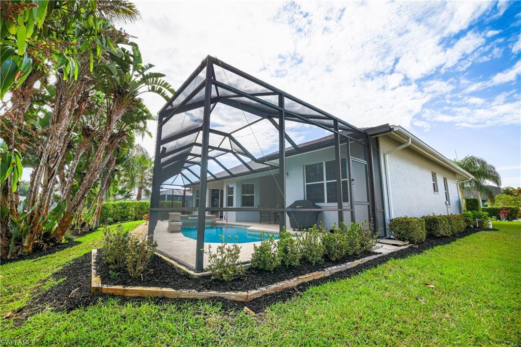 Back of house featuring a sunroom, a patio area, an outdoor pool, a lawn, and stucco siding