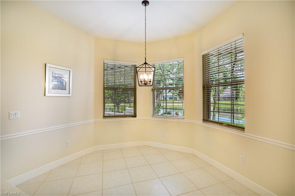 Unfurnished dining area with light tile patterned floors and hanging lights