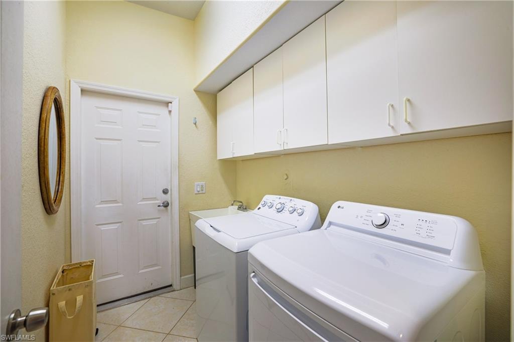 Laundry room featuring washer and clothes dryer, light tile patterned floors, and cabinet space