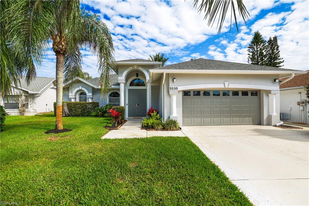 View of front of house featuring a garage, stucco siding, driveway, and a front lawn