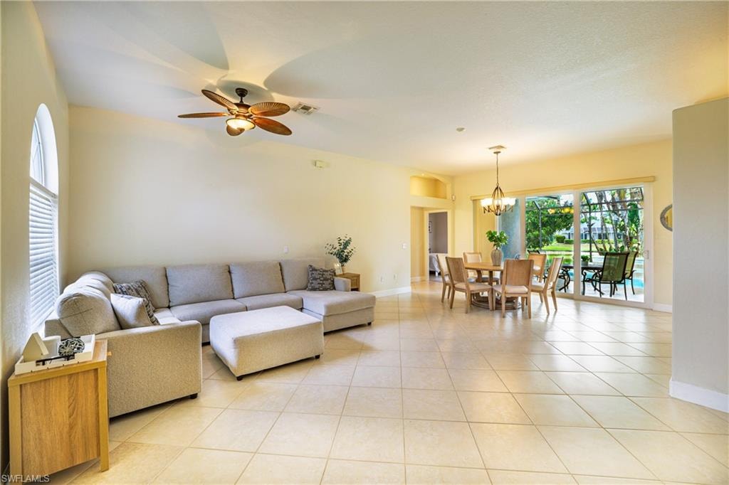 Living room featuring a ceiling fan, light tile patterned floors, and a chandelier