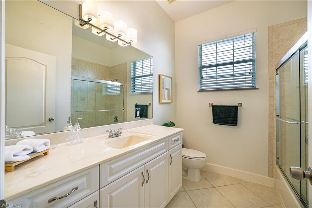 Bathroom featuring vanity, light tile patterned floors, and combined bath / shower with glass door