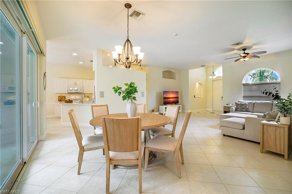 Dining area with a ceiling fan, suspended lighting, arched walkways, and light tile patterned flooring