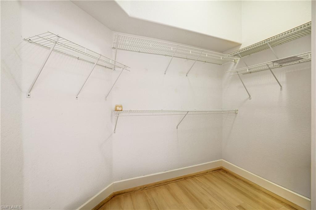 Walk in closet with light wood finished floors