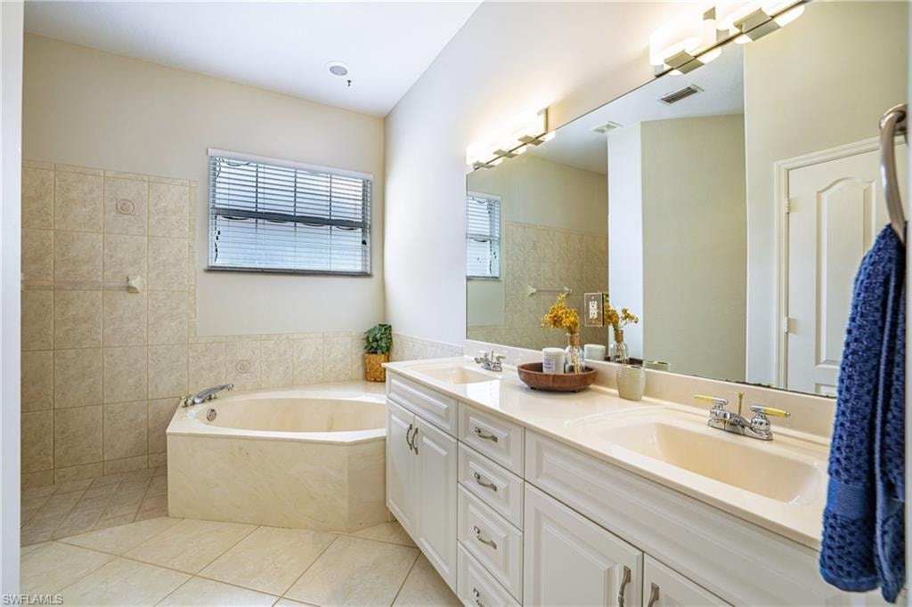 Bathroom with double vanity, a bath, and light tile patterned floors