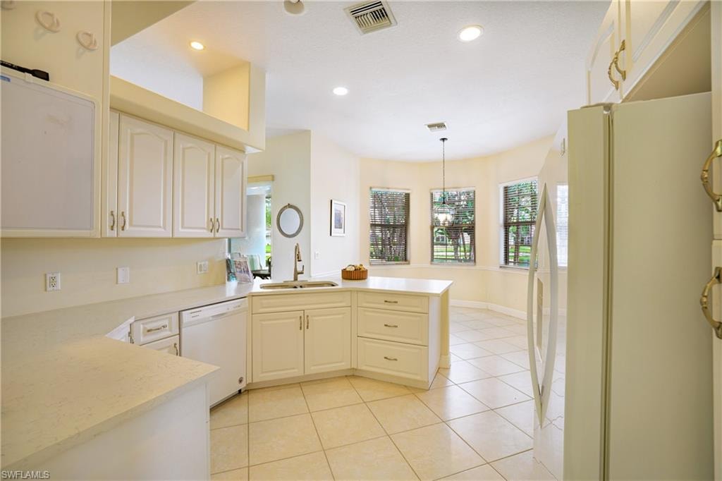 Kitchen featuring white appliances, a peninsula, plenty of natural light, and light tile patterned floors